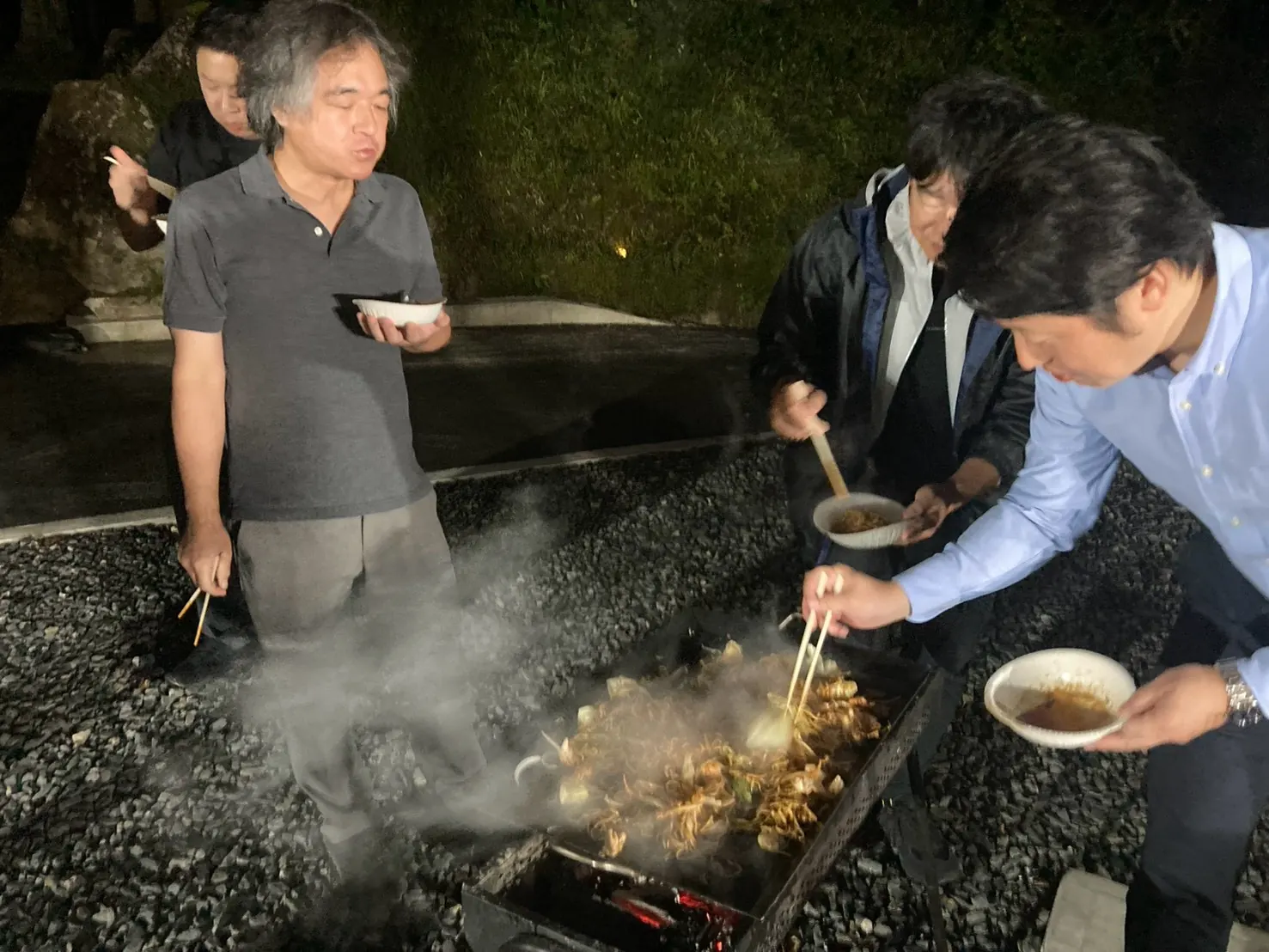 BBQコンロを囲んで食事をする参加者